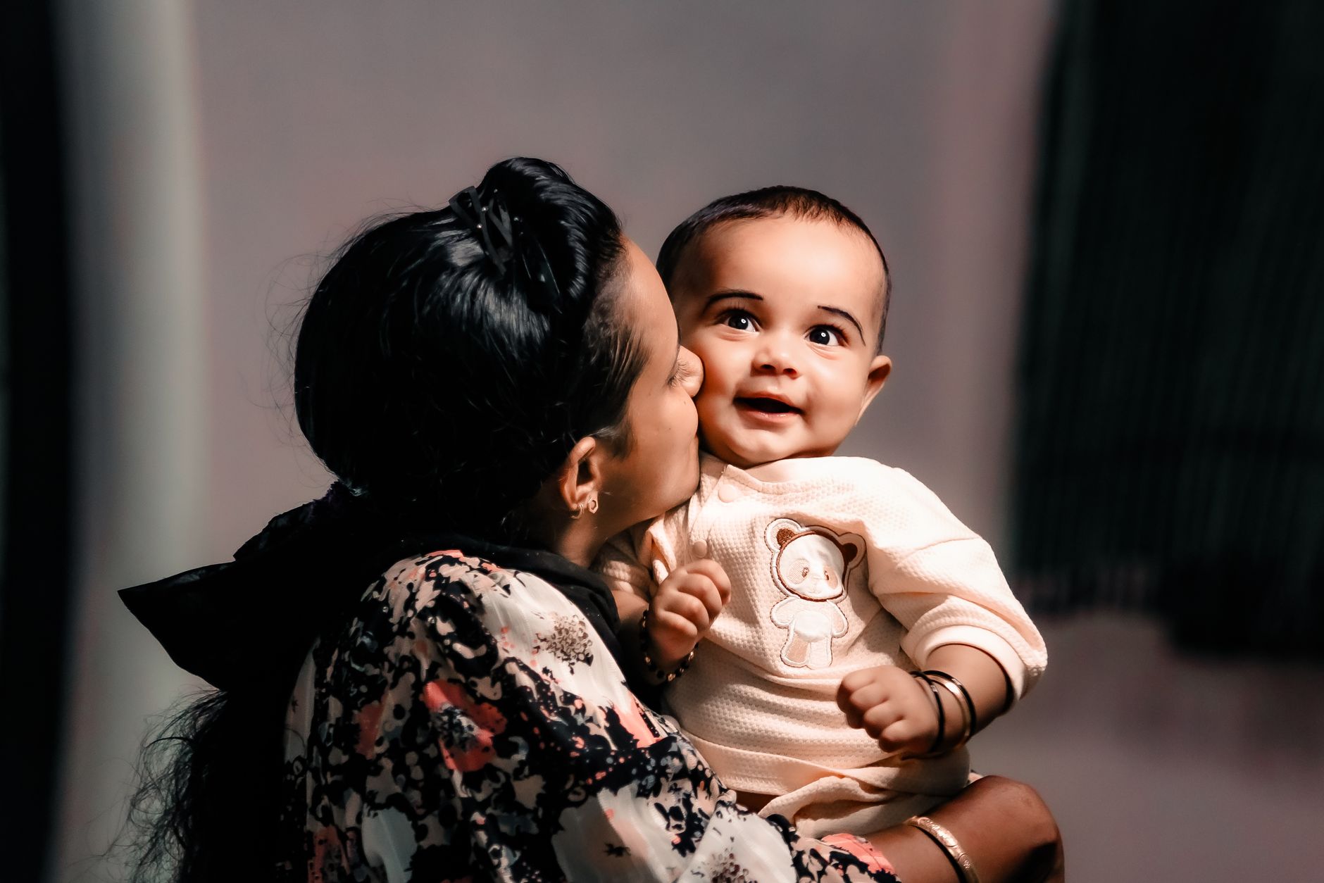 An Indian mother nuzzles and kisses her smiling baby, reconnecting in a warm, tender embrace