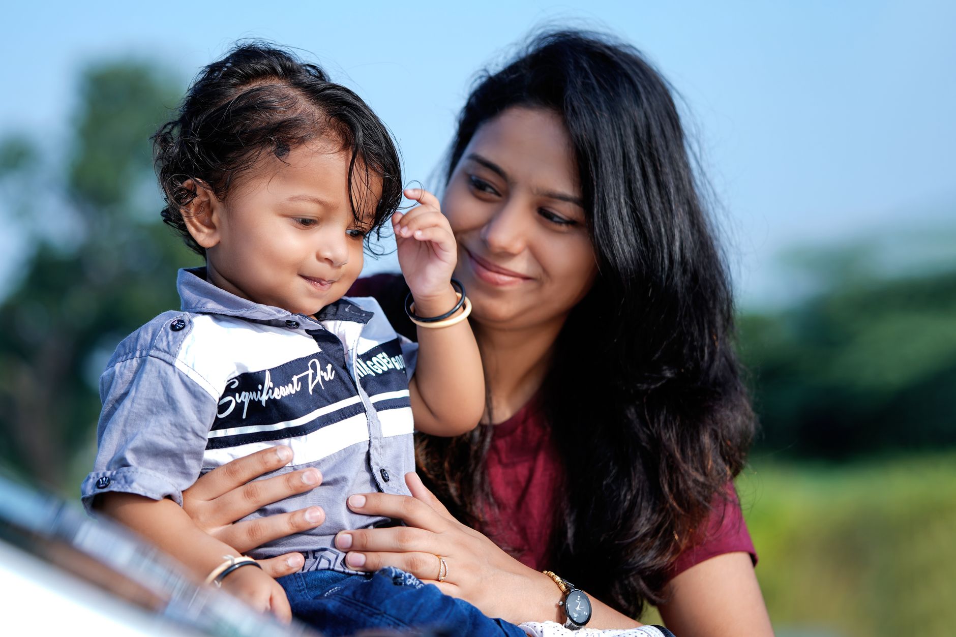 An Indian mother and her toddler son share a joyful, affectionate moment outdoors